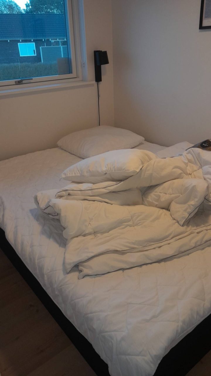 Soveværelset før klargøring, med dyner og pude liggende uredt på sengen
