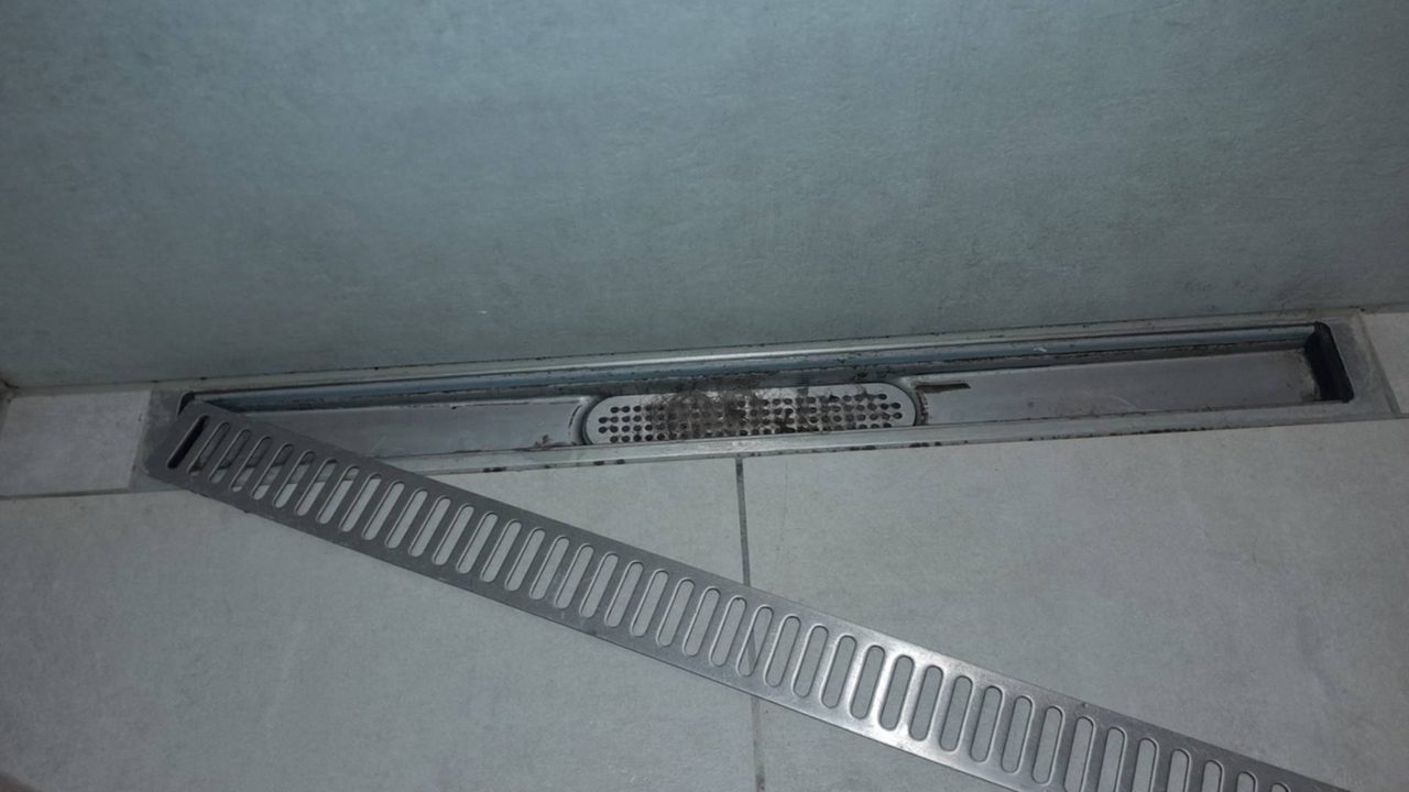 Ablaufrinne in der Dusche mit abgenommenem Gitter; das Sieb im Boden ist mit Haaren und Seifenresten zugesetzt