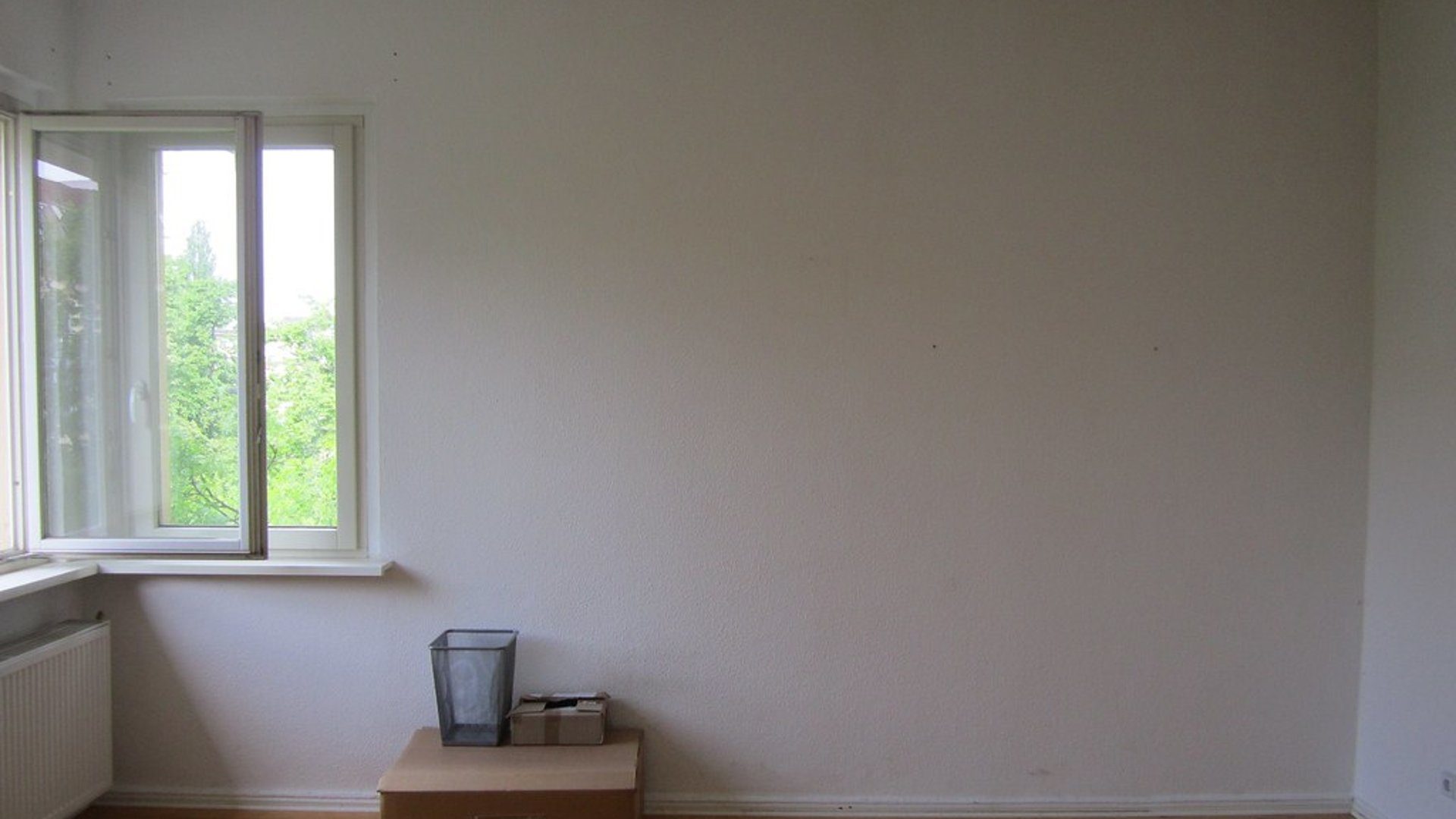 Geräumtes Zimmer mit offenem Fenster und einigen Umzugskartons